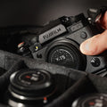 Fujifilm X-T5 with a stealth label resting in a padded camera bag, a hand reaching for it