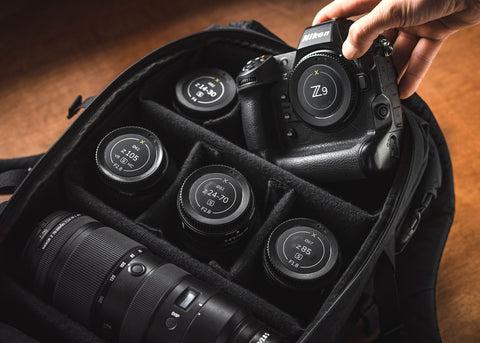 Nikon Z9 camera being placed into a camera bag with lenses.